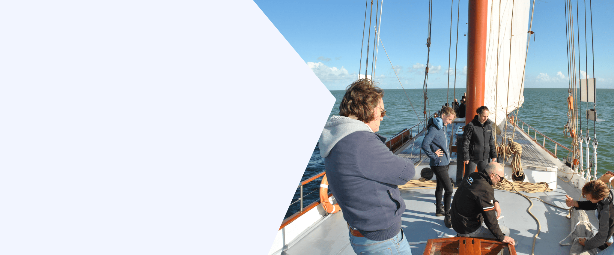 een samenwerkingstraining op een boot van goal trainingen. een groepje mensen is samen een zeil op aan het zetten
