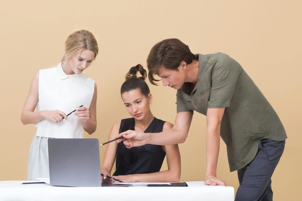 Een groep van 3 medewerkers die de online feedback aan het monitoren is op een laptop.