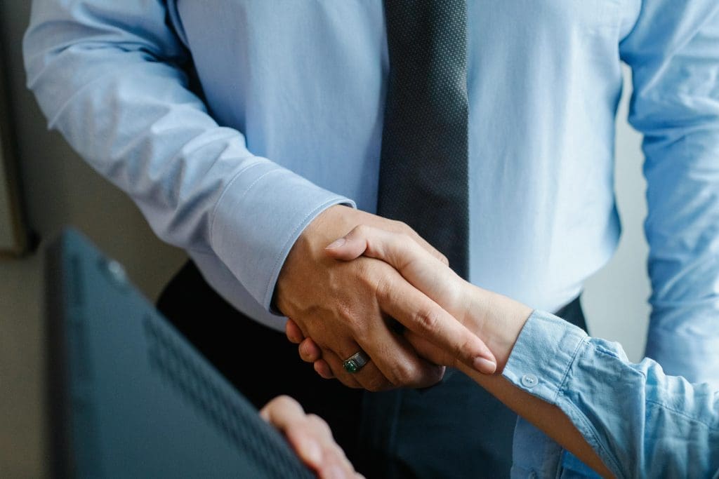 twee mannen in pak die elkaar de hand schudden na een succesvolle onderhandeling